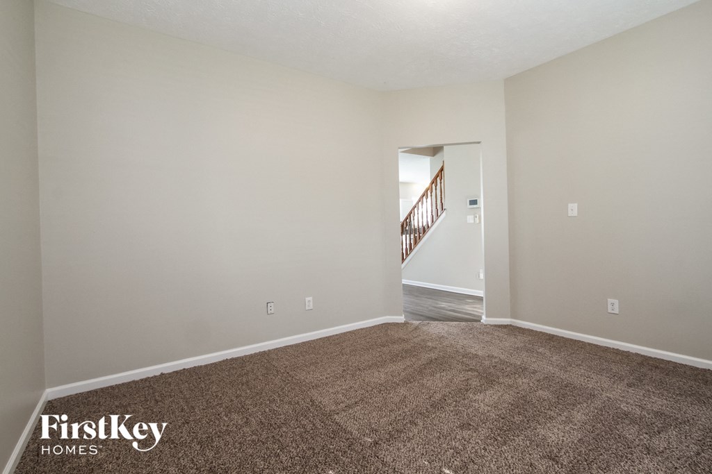 an empty living room with a carpeted floor and a staircase