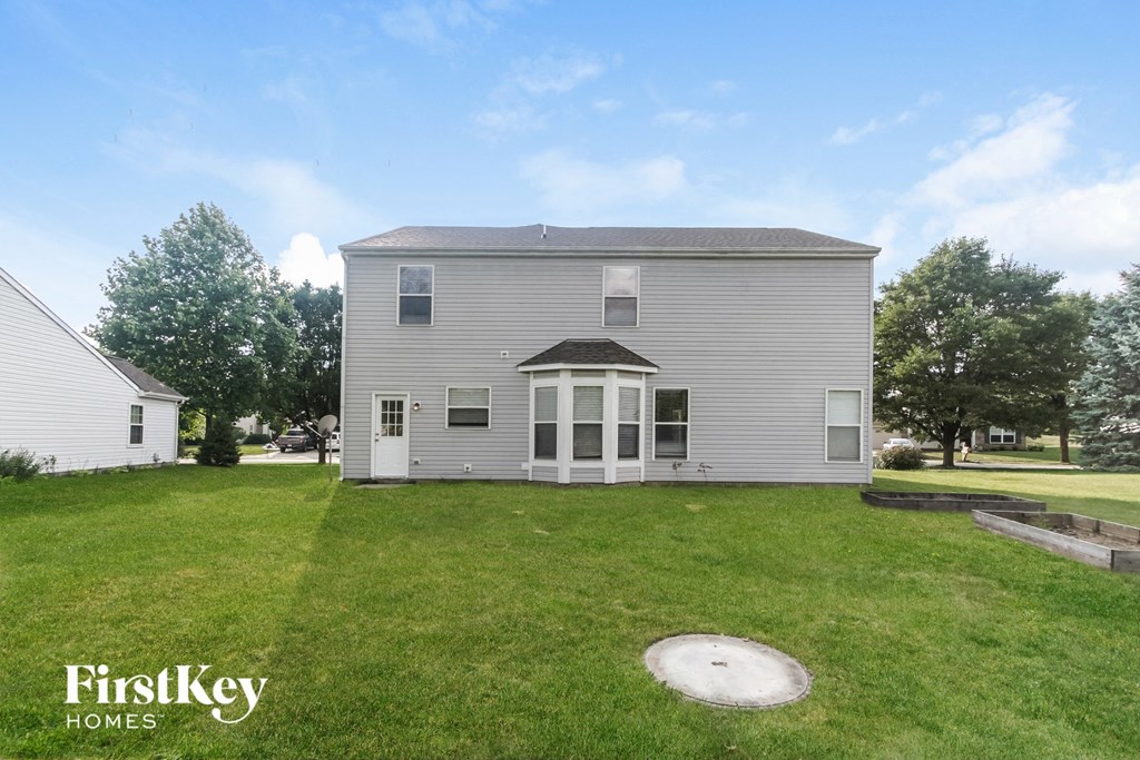 the back of a house with a grassy yard and a white house
