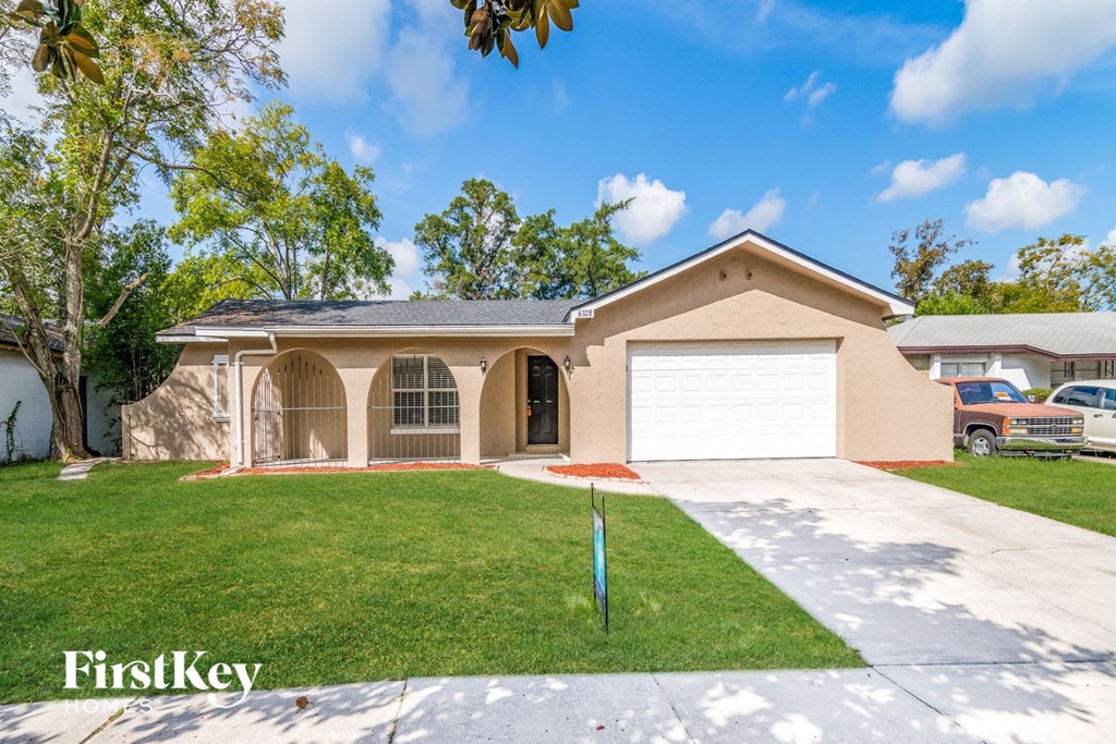 a beige house with a garage and a lawn