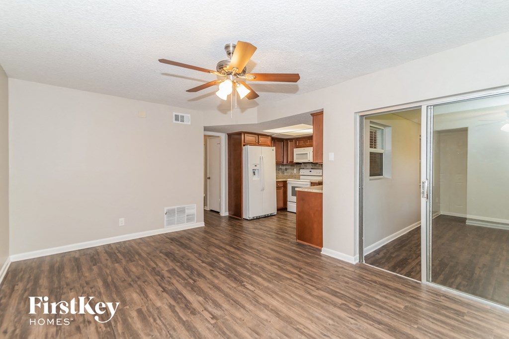 a living room with a ceiling fan and a door to a kitchen