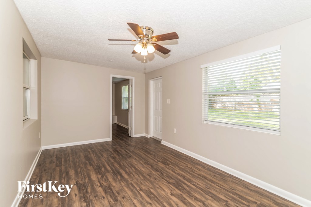 an empty living room with a ceiling fan and a window