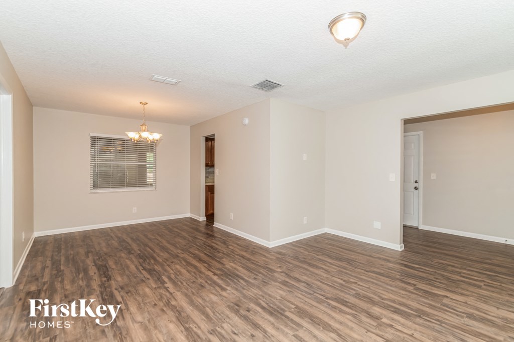the living room and dining room of an empty house with wood flooring