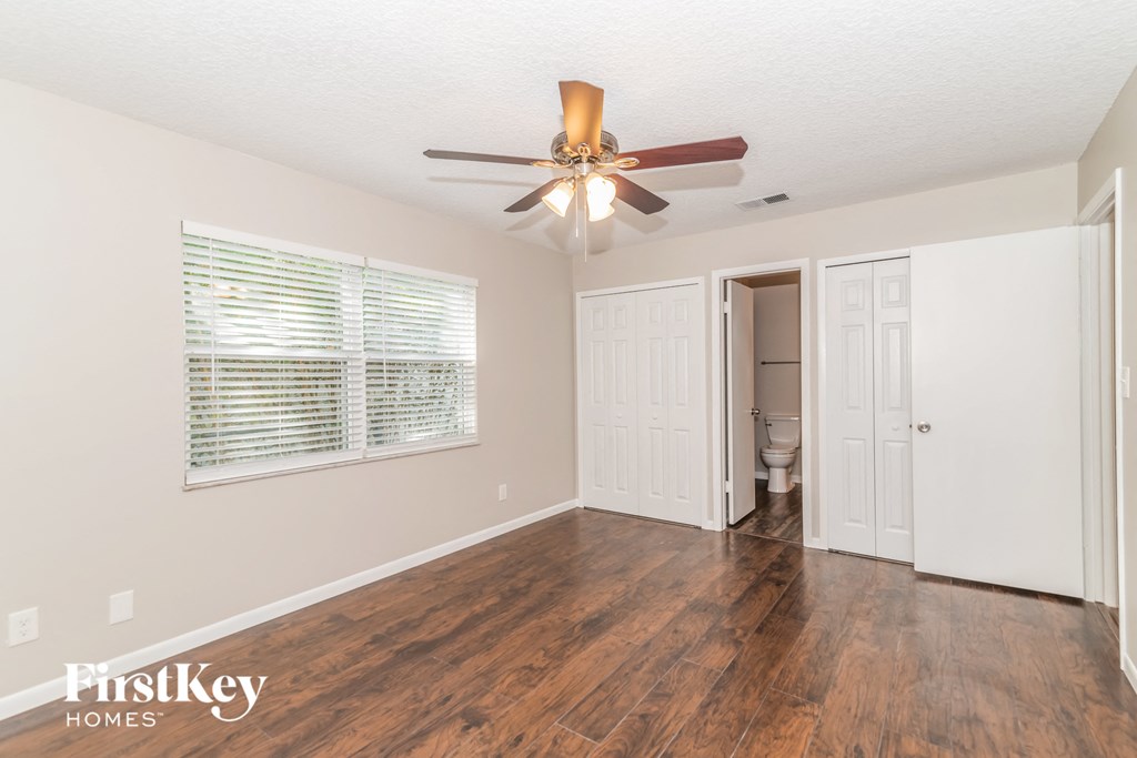 a living room with a ceiling fan and a door to a bathroom