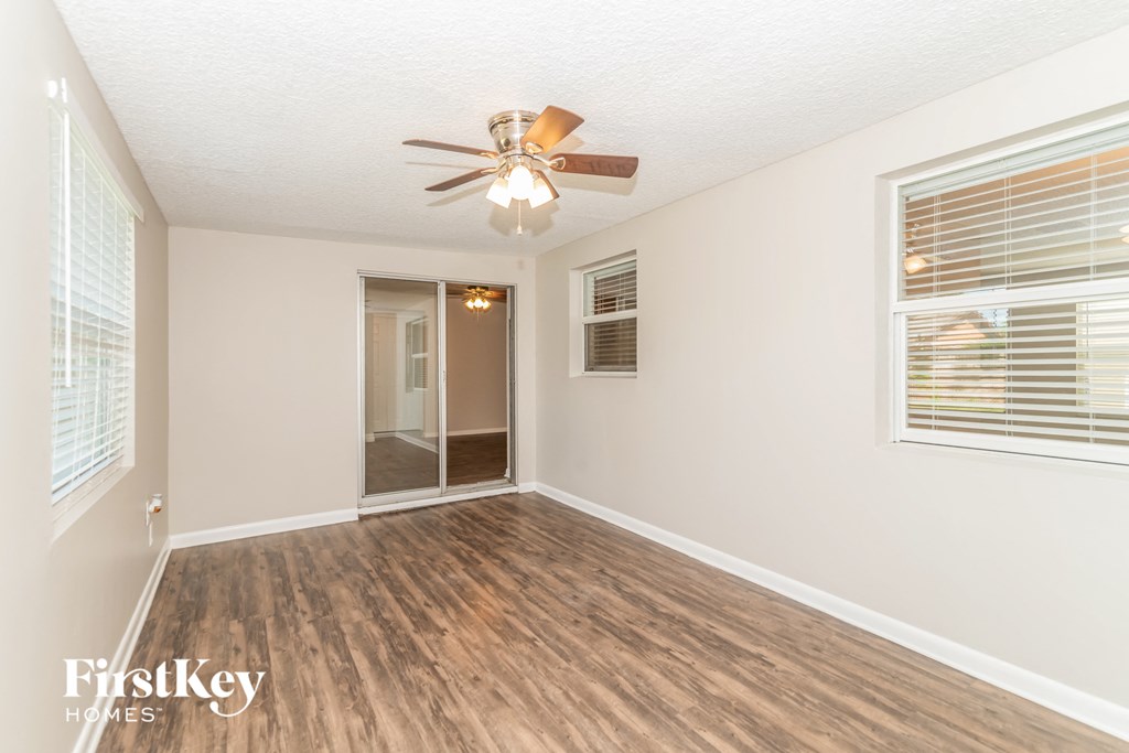 an empty living room with a ceiling fan and a window