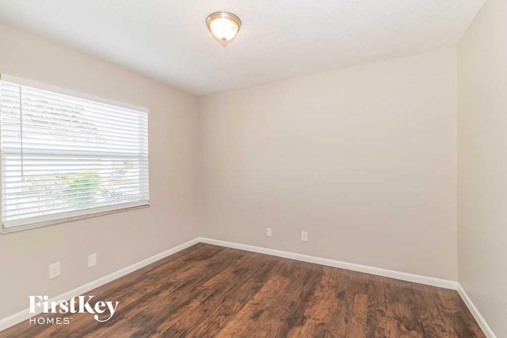 the spacious living room with wood flooring and a large window