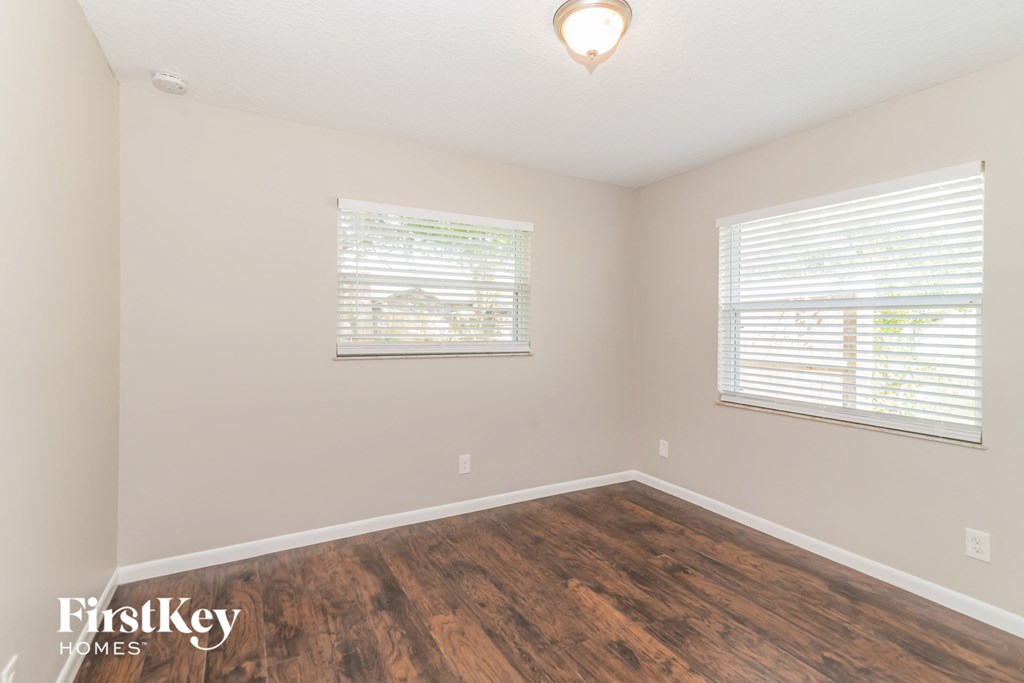 a bedroom with a hard wood floor and two windows