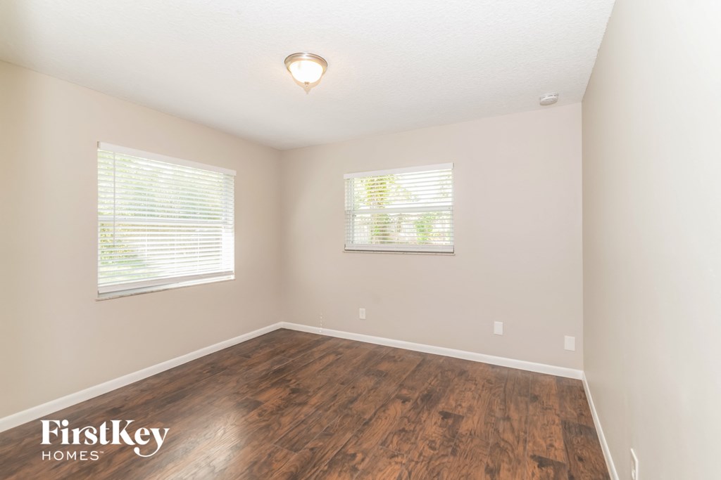 a bedroom with a hard wood floor and two windows