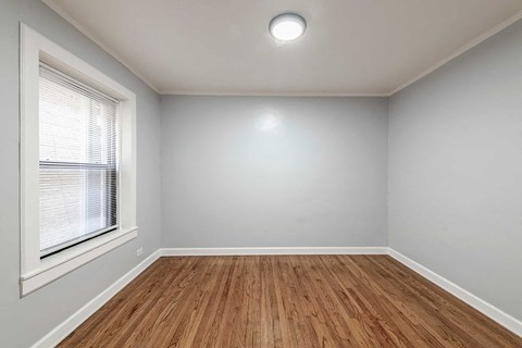 an empty living room with a window and wooden floors