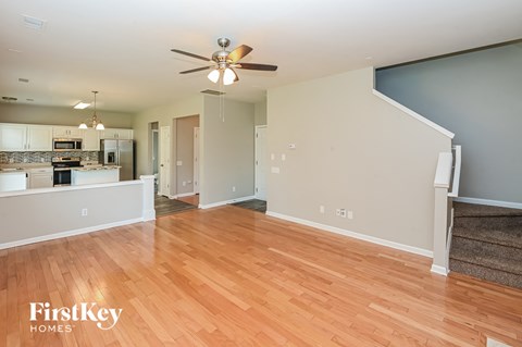 A spacious living room with a wood floor and a ceiling fan.