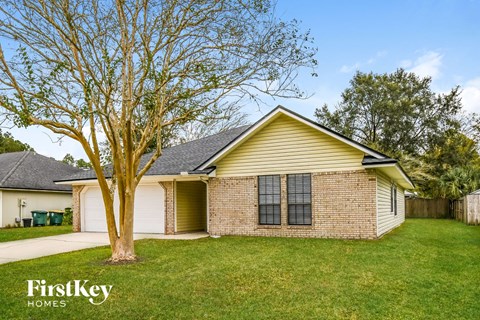 the front of a yellow house with a tree in the yard