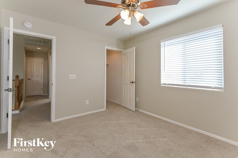 a bedroom with a ceiling fan and a door to a hallway