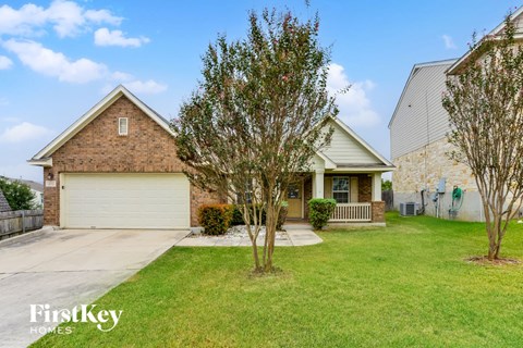 A house with a garage and a tree in front of it.