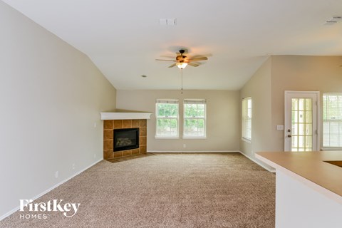 A spacious living room with a fireplace and a ceiling fan.