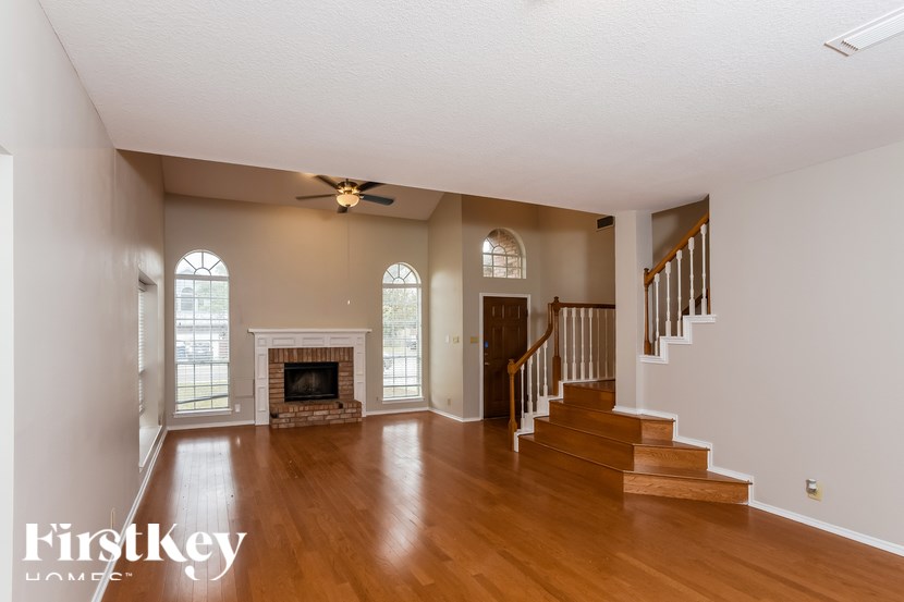 A spacious living room with a fireplace and stairs leading to another room.
