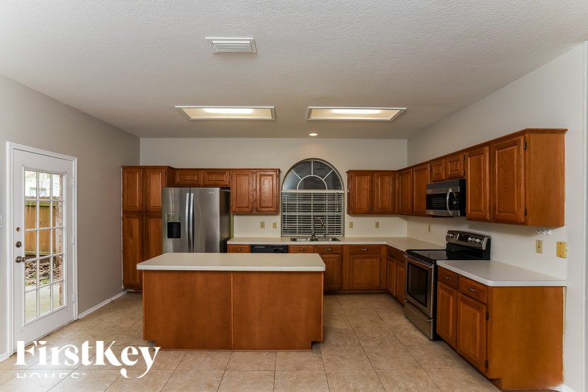 A kitchen with wooden cabinets and a stainless steel refrigerator.