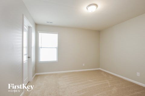 a spacious bedroom with a door to a closet and a window