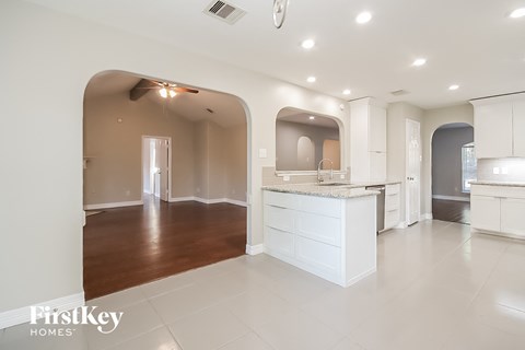 an open kitchen and living room with white cabinets and a white counter top