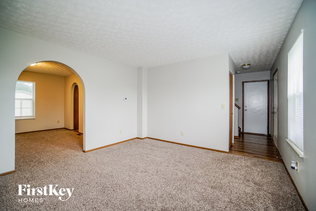 the living room and hallway of an empty house with white walls and carpet