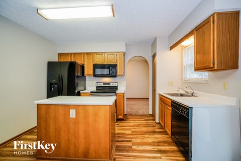 a kitchen with wooden cabinets and black appliances and white counter tops