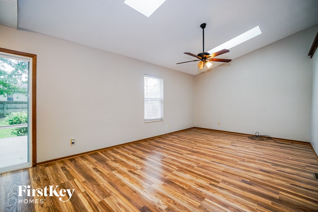 the living room with wood flooring and a ceiling fan