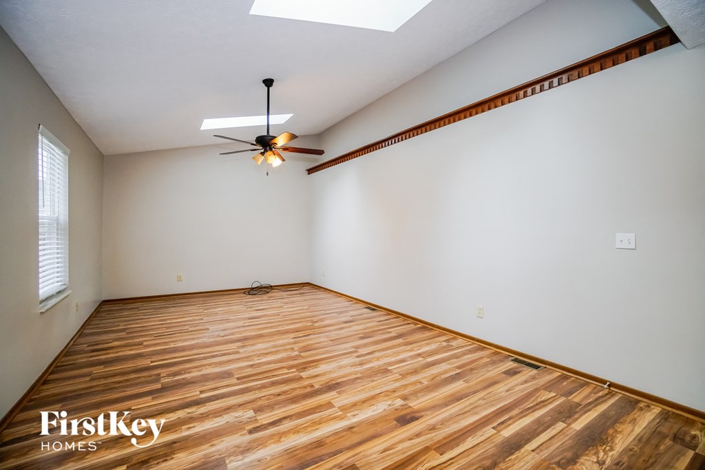 the living room with wood flooring and a ceiling fan