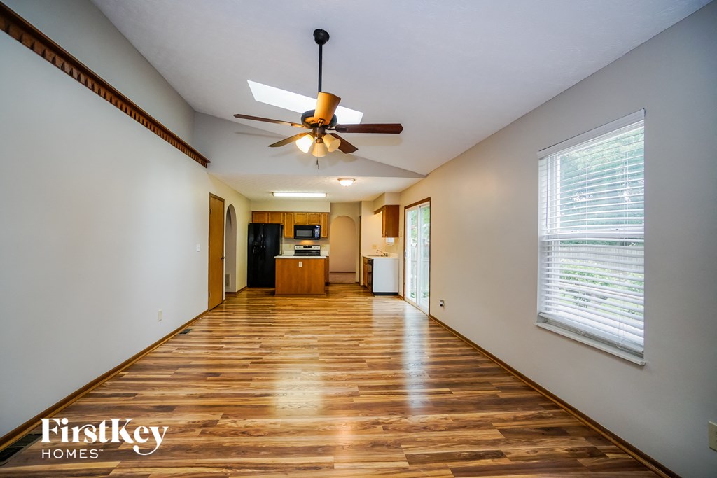 an empty living room with wood floors and a ceiling fan