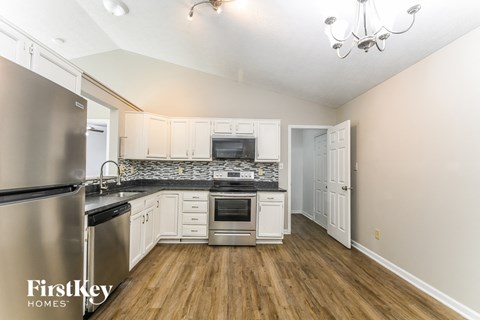 A kitchen with a stainless steel refrigerator and wooden floors.