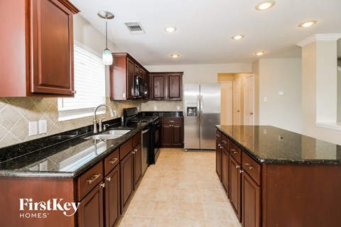 a kitchen with granite counter tops and wooden cabinets and a stainless steel refrigerator