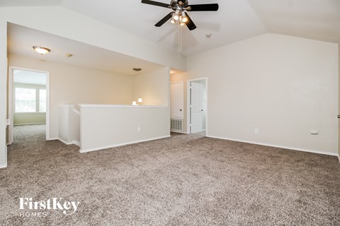 a spacious living room with carpet and a ceiling fan