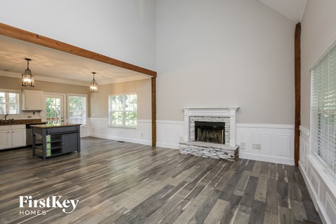 an open living room with a fireplace and a kitchen