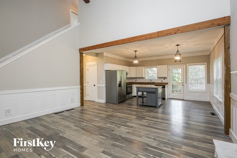 an open kitchen and living room with white walls and wood floors