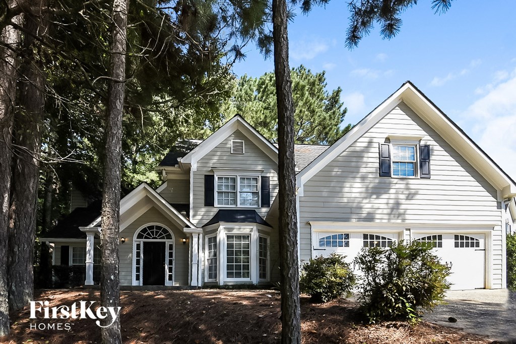 A house with a garage is surrounded by trees.
