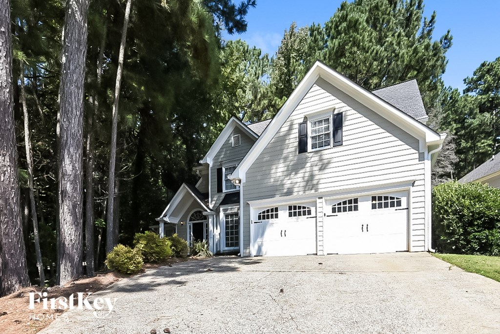A two-story house with a garage is surrounded by trees.