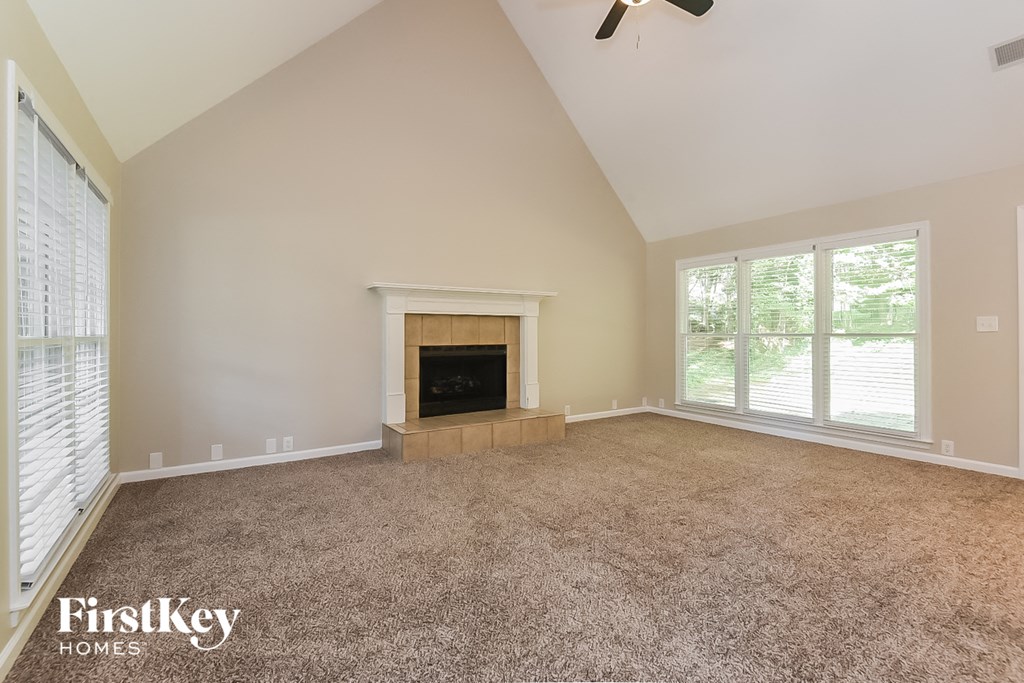 A spacious room with a fireplace and a ceiling fan.