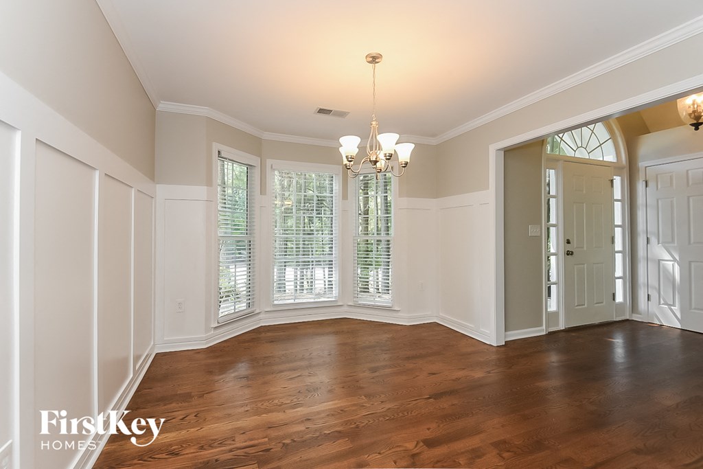 A large empty room with wooden floors and a chandelier.