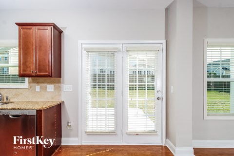 A kitchen with a brown counter top and a white door with blinds.