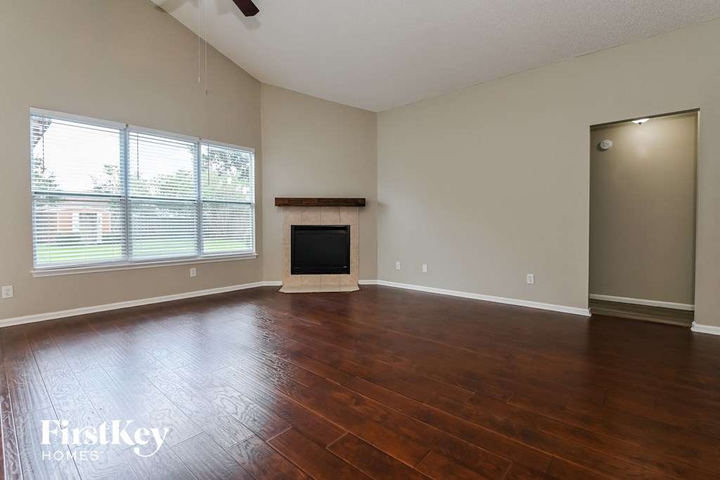 A room with a fireplace and wood flooring.