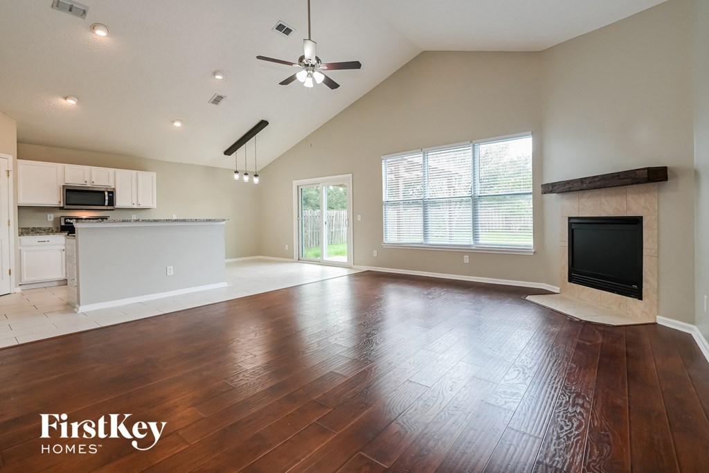 A spacious living room with wood flooring and a fireplace.