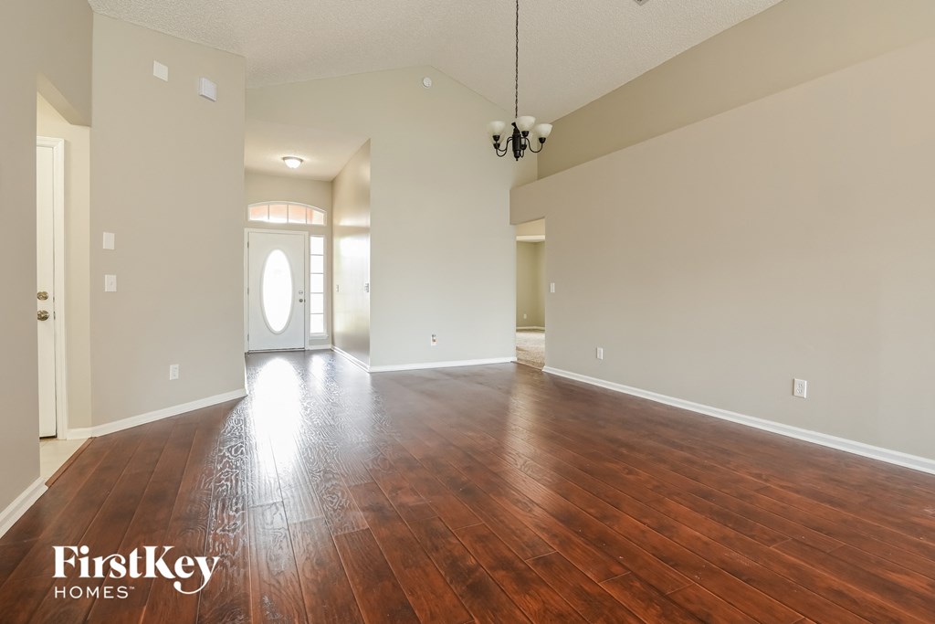 A spacious room with wooden floors and a large window.