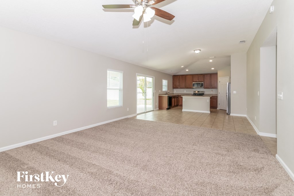 A spacious room with a carpeted floor and a ceiling fan.