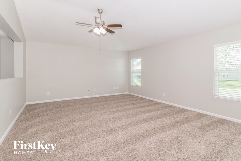 A room with a carpet floor and a ceiling fan.