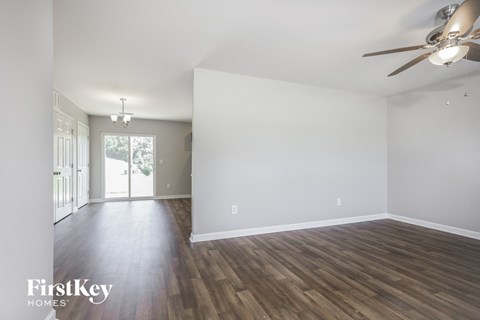 A spacious room with wooden floors and a ceiling fan.