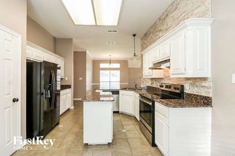A kitchen with white cabinets and a black refrigerator.