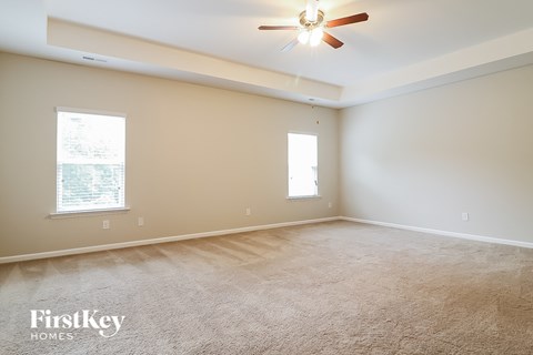 a spacious living room with carpet and a ceiling fan