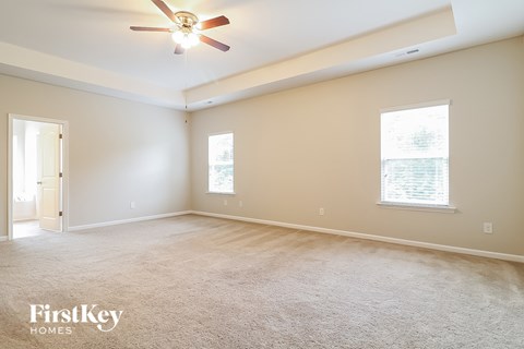 a master bedroom with carpet and a ceiling fan