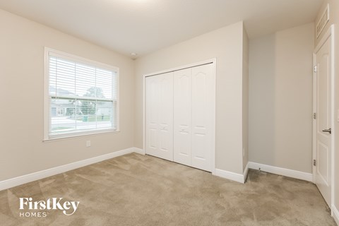 A bedroom with a large window and a white closet.