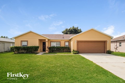 a yellow house with a lawn and a driveway