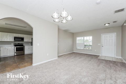 the living room and kitchen of an open floor plan with white cabinets