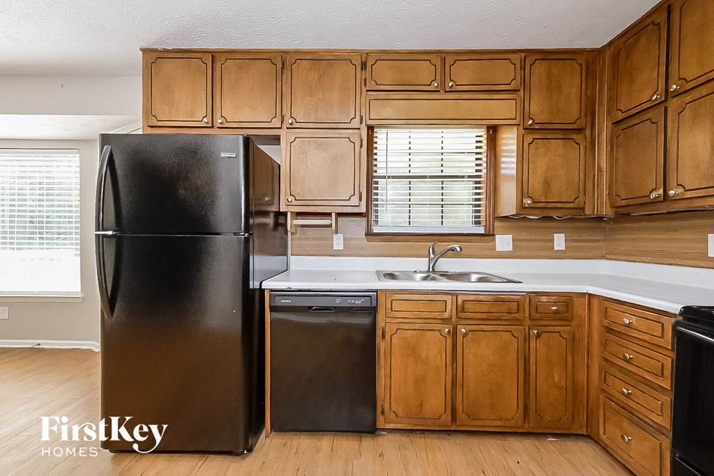 a kitchen with wooden cabinets and a black refrigerator