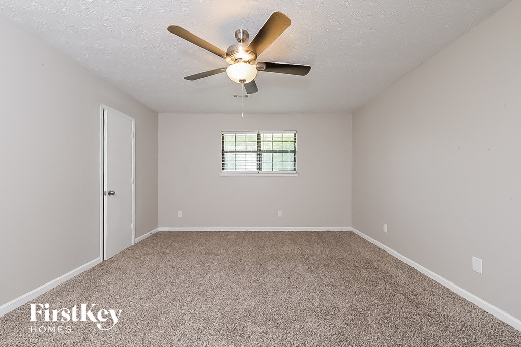 the spacious living room with ceiling fan and carpet
